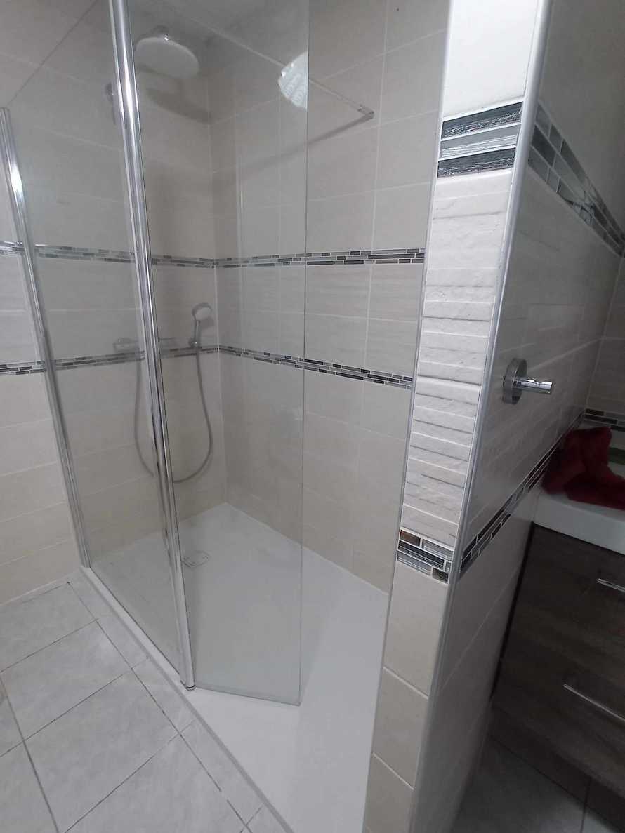 Une grande douche sécurisée d'angle avec un troisième mur construit pour l'encastrer