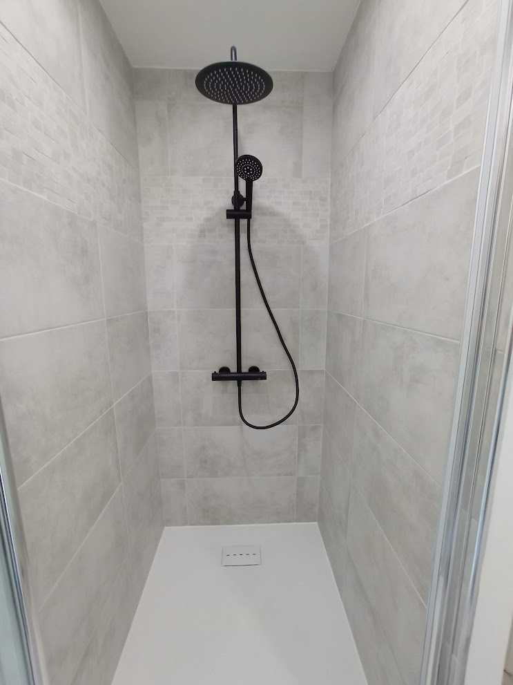 Salle d'eau moderne avec porte coulissante en bois massif et douche Domao noire.