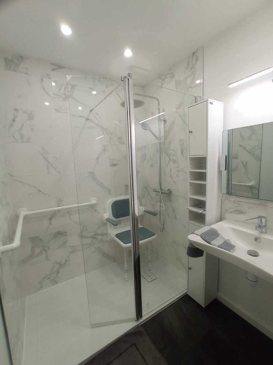 Une grande douche pratique et sécurisée avec barre de maintien et siège